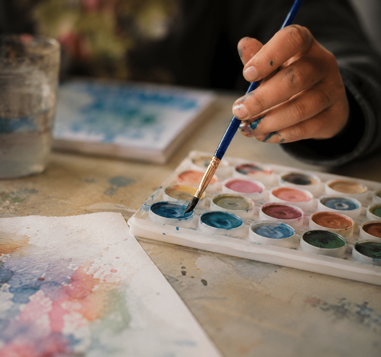 Kind malt mit Wasserfarben in einer kunsttherapeutischen Begleitung